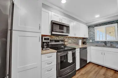 a kitchen with white cabinets and a stainless steel refrigerator at Regency Towers 1121 in Panama City Beach