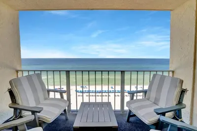 two chairs and a table on a balcony with the beach at Regency Towers 1121 in Panama City Beach