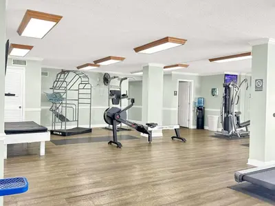 a gym with treadmills and machines in a room at Regency Towers 1121 in Panama City Beach