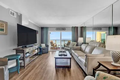 a living room with a couch and a flat screen tv at Regency Towers 1121 in Panama City Beach