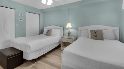 two beds in a bedroom with blue walls and wooden floors at Regency Towers Unit 725 in Panama City Beach