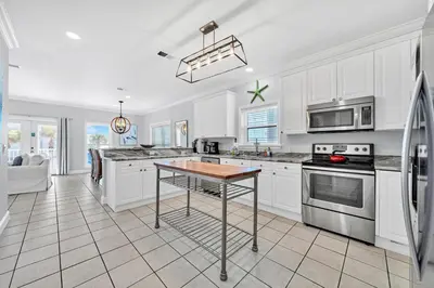 a kitchen with white cabinets and a table at 3 Generations Beach House in Watersound Beach