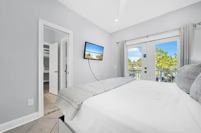 a white bedroom with a large bed and a tv at 3 Generations Beach House in Watersound Beach