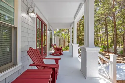 a porch with red chairs on a white house at Almost Heaven in Watersound Proper INCLUDES Carriage House! Bedding for 12 in Rosemary Beach