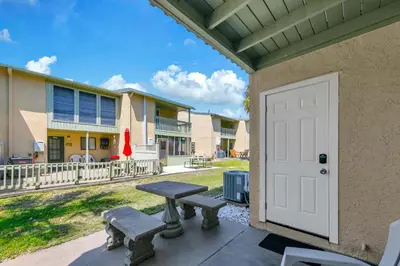 a porch with a picnic table and a white door at Gulf Highlands 108 in Panama City Beach