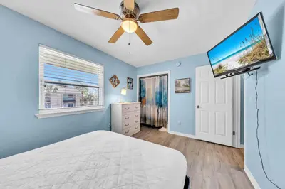 a bedroom with a ceiling fan and a flat screen tv at Gulf Highlands 108 in Panama City Beach