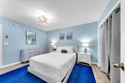 a bedroom with a white bed and blue walls at Gulf Highlands 108 in Panama City Beach