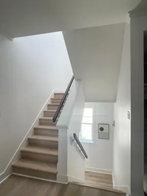 a staircase in a house with white walls and wooden floors at Moonlight and Starlight Escape in Panama City Beach