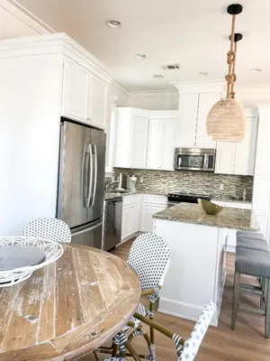 a kitchen with white cabinets and a table with chairs at Moonlight and Starlight Escape in Panama City Beach