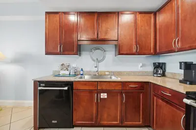 a kitchen with wooden cabinets and a sink at Laketown Wharf #1404 by Nautical Properties in Panama City Beach