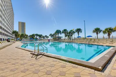 a swimming pool in a resort with palm trees at Steps to Shore PCB Condo with Pool Access and Views! in Panama City Beach