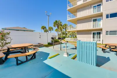 a patio with picnic tables in front of a building at Steps to Shore PCB Condo with Pool Access and Views! in Panama City Beach