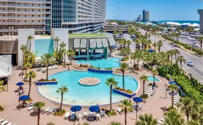an aerial view of a pool with palm trees and buildings at Low Floor 3BD plus Bunks Condo! Family Resort! 5 Pools! Free Beach Chair Service! in Panama City Beach