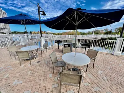 two tables and chairs with umbrellas on a patio at Low Floor 3BD plus Bunks Condo! Family Resort! 5 Pools! Free Beach Chair Service! in Panama City Beach