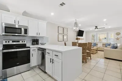 a kitchen with white cabinets and appliances and a living room at La Costeñita in Panama City Beach