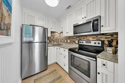 a kitchen with white cabinets and a stainless steel refrigerator at Horizon South 40C- Good Vibes in Panama City Beach