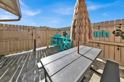 a wooden bench on a patio with a table and chairs at Horizon South 40C- Good Vibes in Panama City Beach