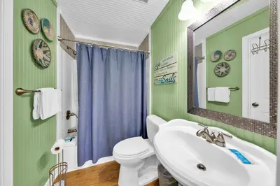 a bathroom with a sink and a toilet and a mirror at Horizon South 40C- Good Vibes in Panama City Beach