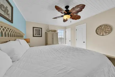 a bedroom with a large white bed with a ceiling fan at Horizon South 40C- Good Vibes in Panama City Beach