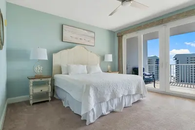 a bedroom with a white bed and a balcony at Laketown Wharf #721 by Nautical Properties in Panama City Beach