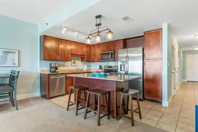 a kitchen with wooden cabinets and a island with bar stools at Laketown Wharf #721 by Nautical Properties in Panama City Beach