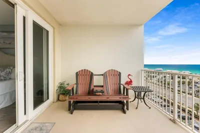two chairs and a table on a balcony with the ocean at Laketown Wharf #721 by Nautical Properties in Panama City Beach