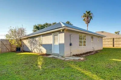 a small house in a yard with a palm tree at Family-Friendly PCB Vacation Rental, Walk to Beach in Panama City Beach