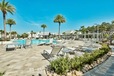 a pool at a resort with chairs and palm trees at Prominence on 30A Homes by Panhandle Getaways in Watersound Beach