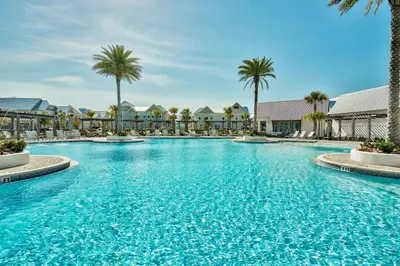 a large swimming pool with palm trees and buildings at Prominence on 30A Homes by Panhandle Getaways in Watersound Beach