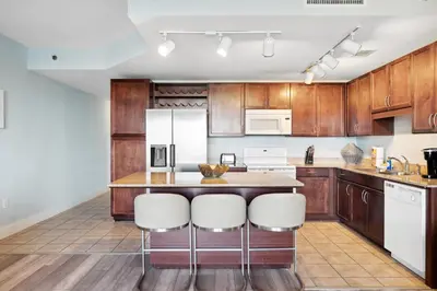 a kitchen with wooden cabinets and a island with bar stools at Laketown Wharf #302 by Nautical Properties in Panama City Beach