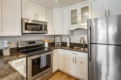 a kitchen with white cabinets and a stainless steel refrigerator at Charming PCB Condo with Balcony Walk to Beach! in Panama City Beach