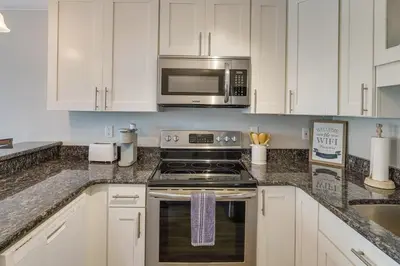 a kitchen with a stove and a microwave at Charming PCB Condo with Balcony Walk to Beach! in Panama City Beach