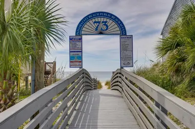 a boardwalk to the beach with a clock on it at Charming PCB Condo with Balcony Walk to Beach! in Panama City Beach