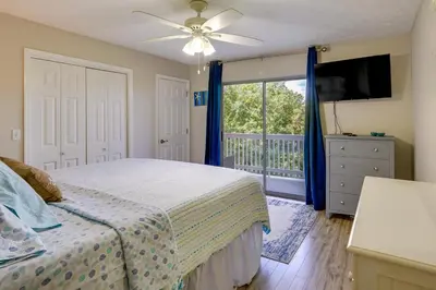 a bedroom with a bed and a television and a balcony at Charming PCB Condo with Balcony Walk to Beach! in Panama City Beach