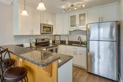 a kitchen with white cabinets and a stainless steel refrigerator at Charming PCB Condo with Balcony Walk to Beach! in Panama City Beach