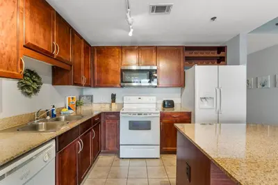 a kitchen with wooden cabinets and white appliances at Laketown Wharf #311 by Nautical Properties in Panama City Beach