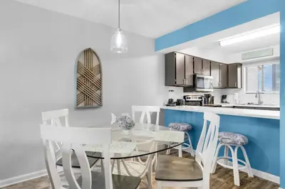 a dining room and kitchen with a glass table and white chairs at Portside I5 in Panama City Beach
