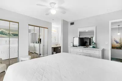 a white bedroom with a large bed and a flat screen tv at Portside I5 in Panama City Beach