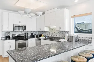a kitchen with white cabinets and granite counter tops at Family Tides Beach House by Panhandle Getaways in Panama City Beach