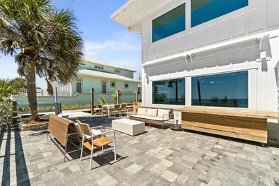 a patio with chairs and tables and a building at Family Tides Beach House by Panhandle Getaways in Panama City Beach