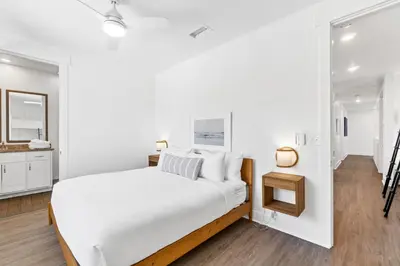 a white bedroom with a bed and a bathroom at Family Tides Beach House by Panhandle Getaways in Panama City Beach