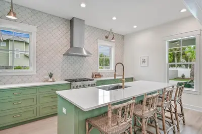 a kitchen with green cabinets and a kitchen island with stools at 30 A-mazing in Santa Rosa Beach