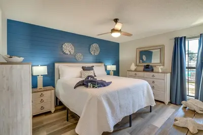 a bedroom with a bed with a blue wall at Walk to Ocean Condo with Pool and Hot Tub in PCB! in Panama City Beach