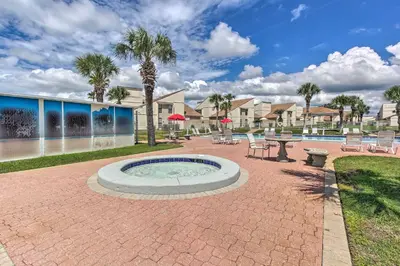 a patio with a hot tub and tables and chairs at Walk to Ocean Condo with Pool and Hot Tub in PCB! in Panama City Beach