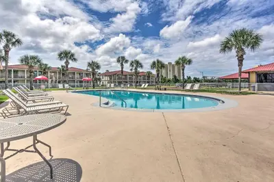 a swimming pool with two chairs and a table at Walk to Ocean Condo with Pool and Hot Tub in PCB! in Panama City Beach
