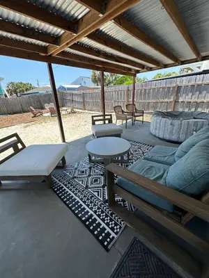 a patio with a couch and a table and chairs at Beachside Bliss - Breakfast, Walk to Schooners, Sleeps 15, Fenced Privacy in Panama City Beach
