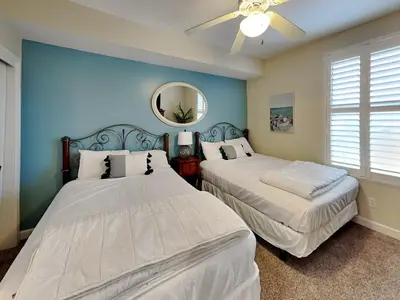 two beds in a room with blue walls and a mirror at Grandview East #403 in Panama City Beach