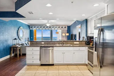 a kitchen with white cabinets and blue walls at Treasure Island #1207 in Panama City Beach