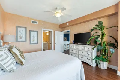 a bedroom with a white bed and a flat screen tv at Treasure Island #1207 in Panama City Beach