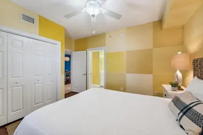 a bedroom with a white bed and yellow walls at Treasure Island #1207 in Panama City Beach